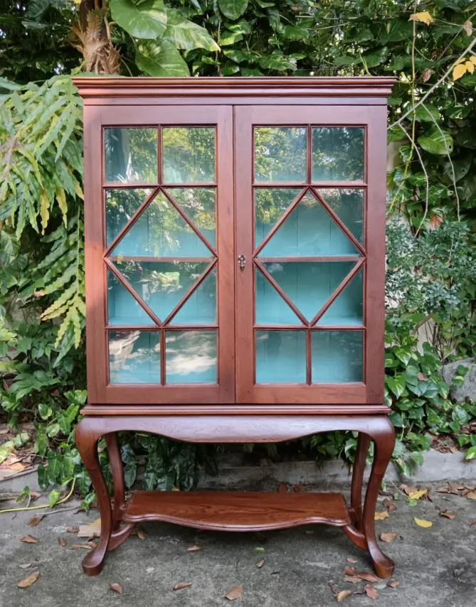 Front view of the teak bookcase with diamond-pattern glass doors and a mint-blue interior