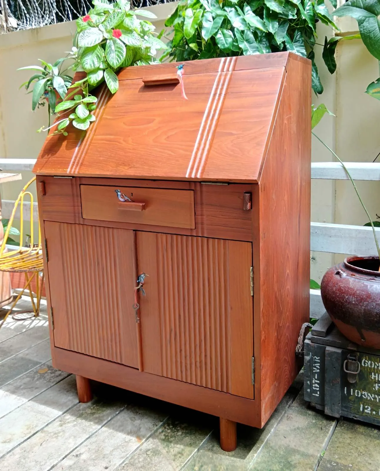 A restored teak cabinet on a sunny veranda