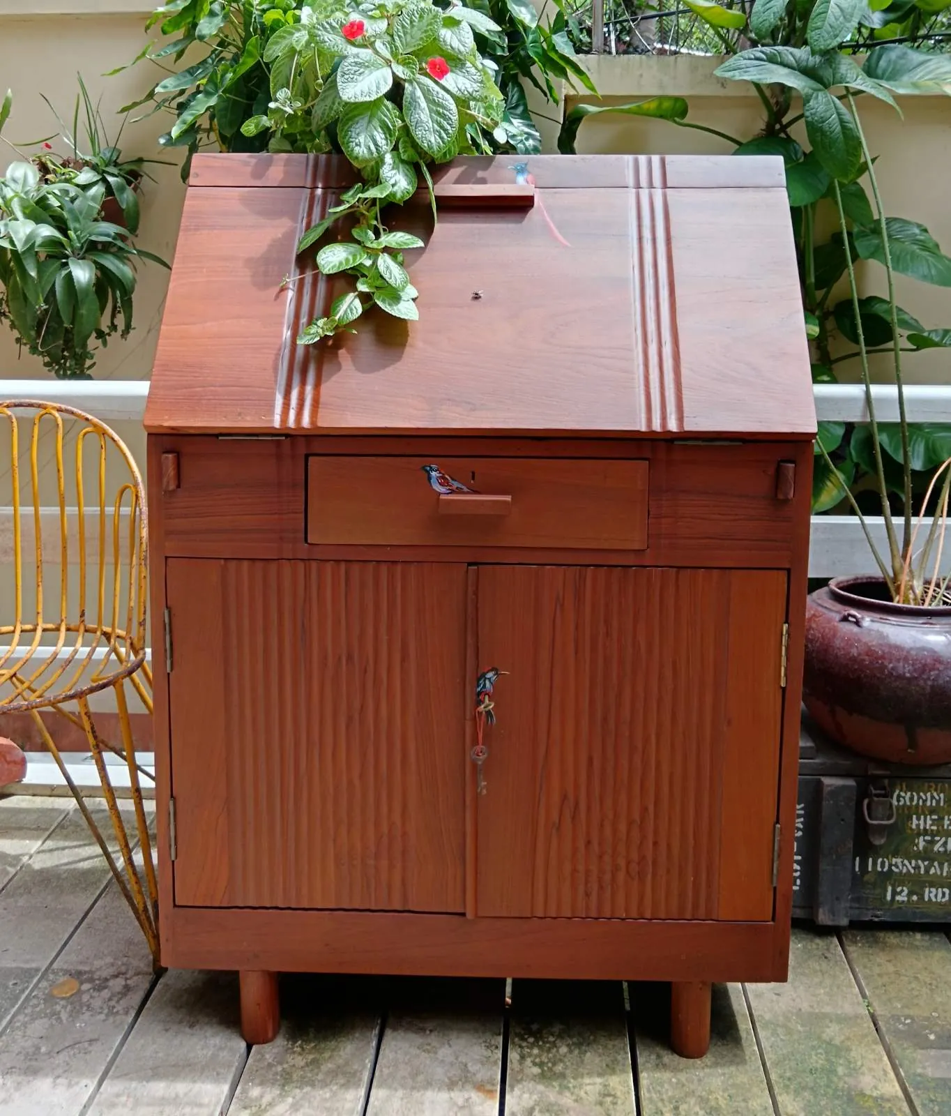 Restored teak cabinet with a slanted lid, styled with plants